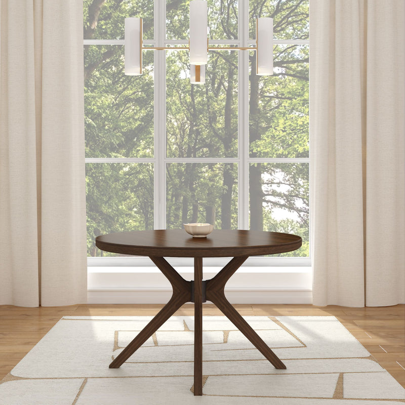 Round wooden dining table in modern living room with large windows and white curtains.