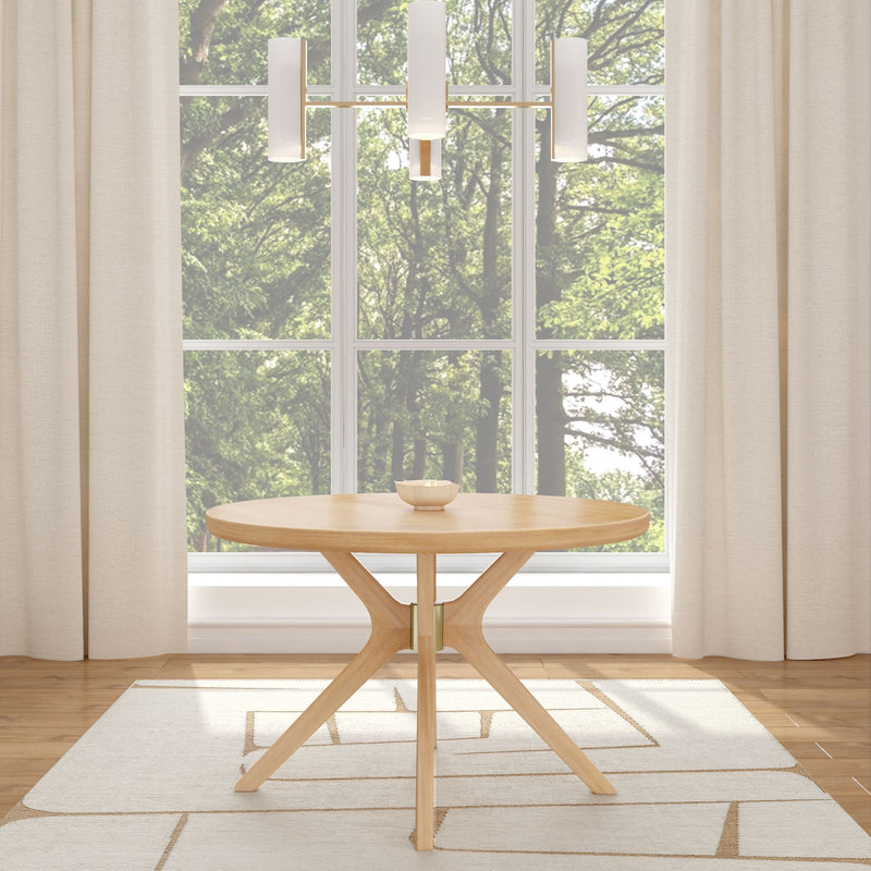 Modern round wooden dining table in bright room with large windows and elegant chandelier.