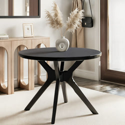 Round black pedestal table with ceramic donut vase holding pampas grass beside a wooden console with arched cutouts in a neutral Scandinavian entryway decor