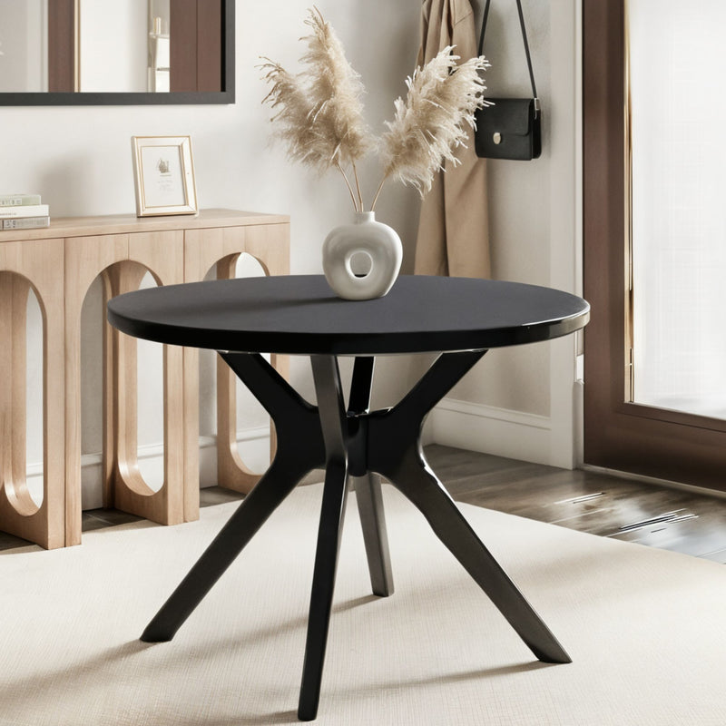 Round black pedestal table with ceramic donut vase holding pampas grass beside a wooden console with arched cutouts in a neutral Scandinavian entryway decor