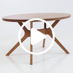 Round wooden dining table with modern design and crossed legs.
