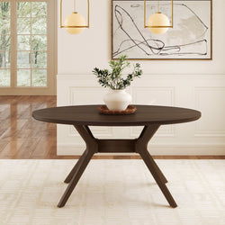 Modern round dining table in a bright room with wooden flooring, featuring a white potted plant centerpiece.