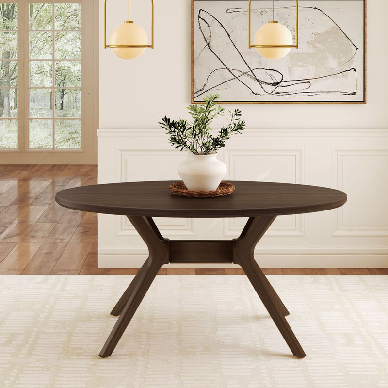 Modern round dining table in a bright room with wooden flooring, featuring a white potted plant centerpiece.