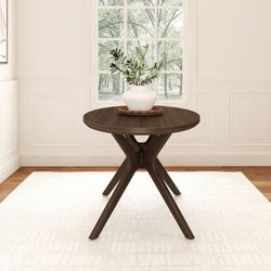 Round wooden dining table with plant centerpiece in modern bright dining room.
