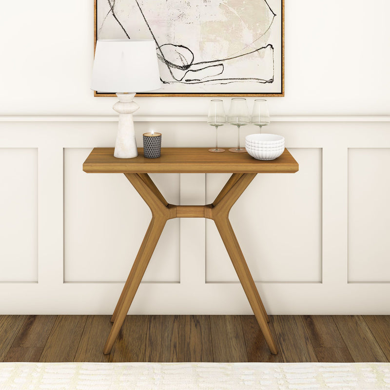 Mid-century modern console table with décor accents including a lamp, candle, glasses, and bowls against a paneled wall.