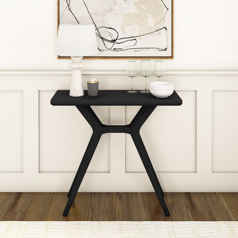 Modern black console table with decorative items against a paneled wall in a stylish interior.