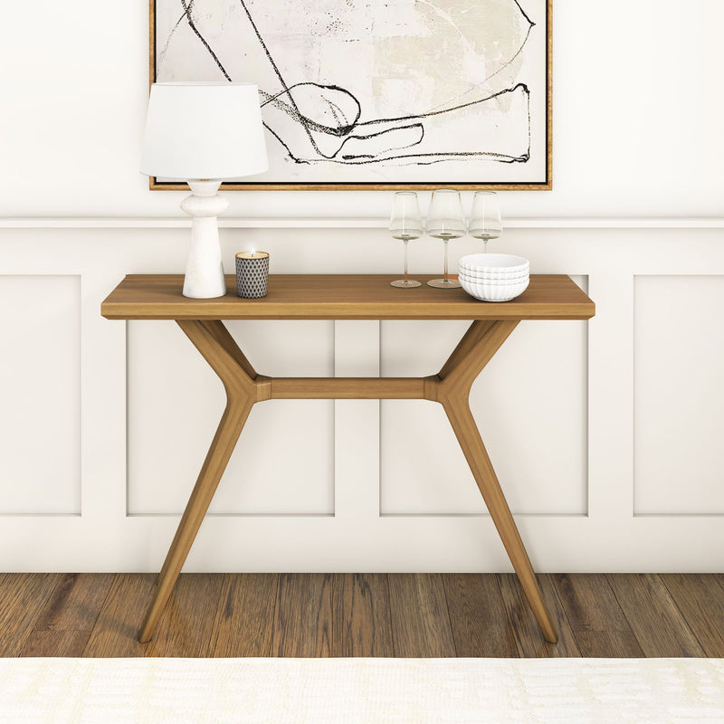 Modern wooden console table with decorative white lamp, candle, and wall art in stylish living room setting.