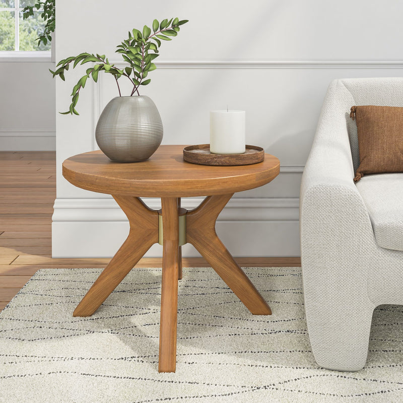 Wooden round side table with a modern vase and candle, next to a white sofa in a stylish living room.