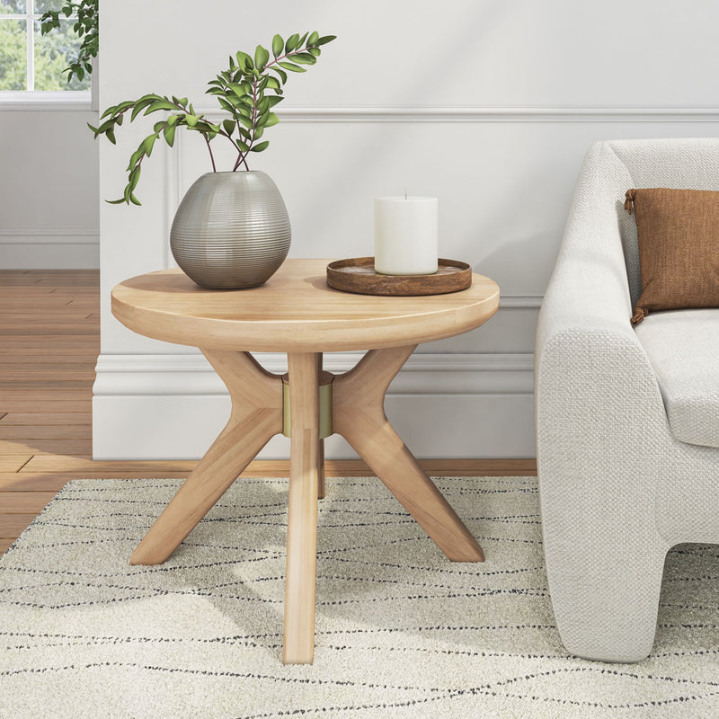 Round wooden side table with modern vase and candle next to a beige sofa in a stylish living room.