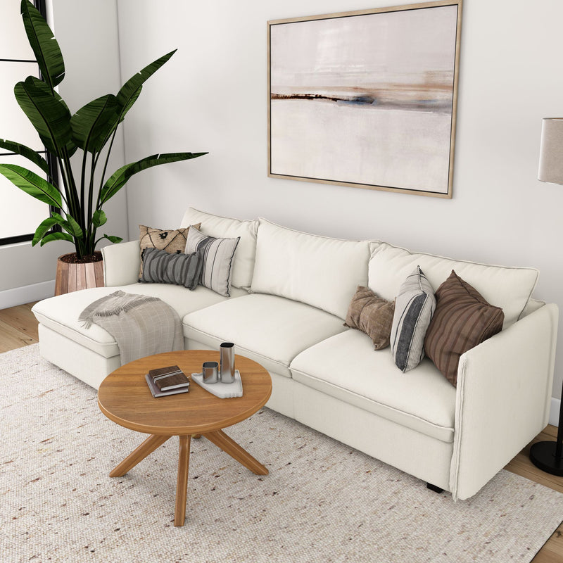 Modern living room with beige sectional sofa, wooden coffee table, abstract wall art, indoor plant, and cozy decorative pillows.