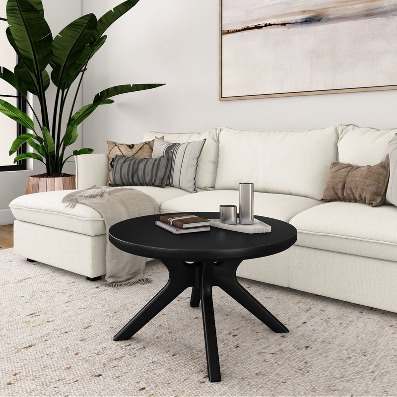 Modern living room with white sectional sofa, black round coffee table, and large potted plant.