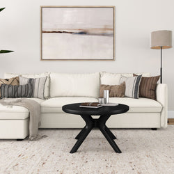 Minimalist living room with white sectional sofa, abstract wall art, and modern black coffee table.