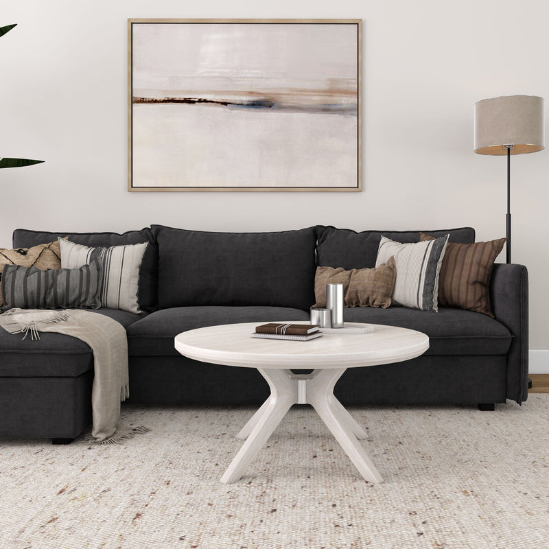 Modern living room with black sofa, abstract wall art, round coffee table, and decorative pillows.