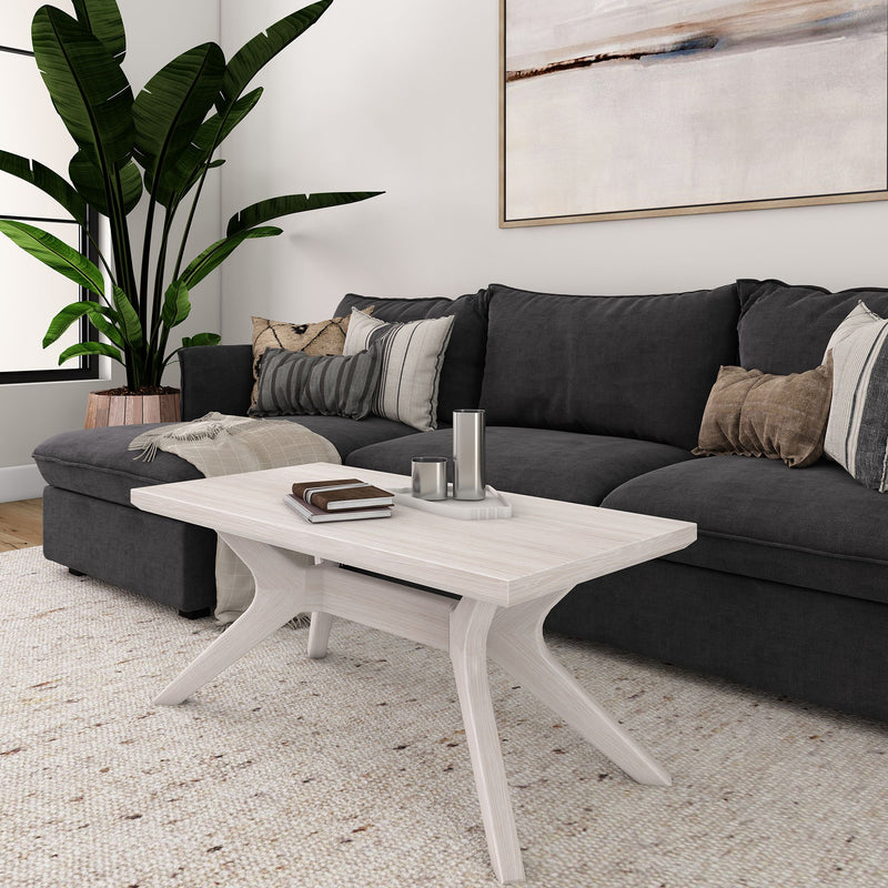 Modern living room with a dark gray sofa, white wooden coffee table, and green indoor plant.