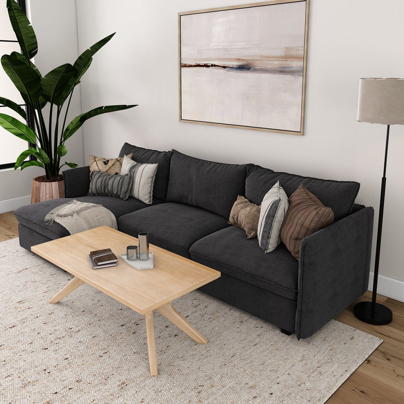 Modern living room with dark gray sectional sofa, wooden coffee table, stylish floor lamp, and indoor plant.