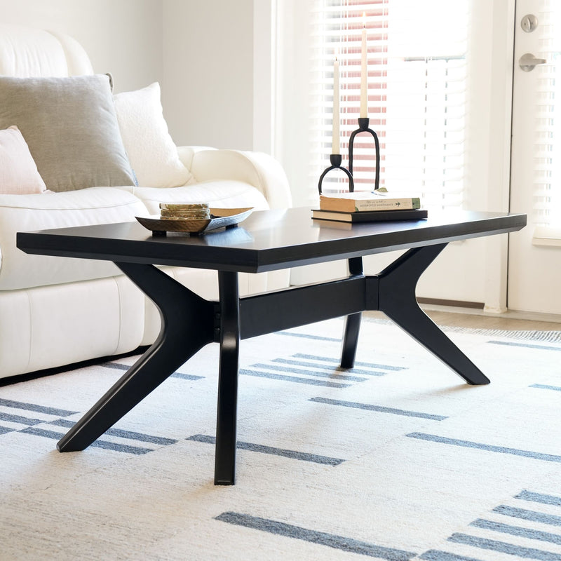 Modern black coffee table in a bright living room with books and candles.
