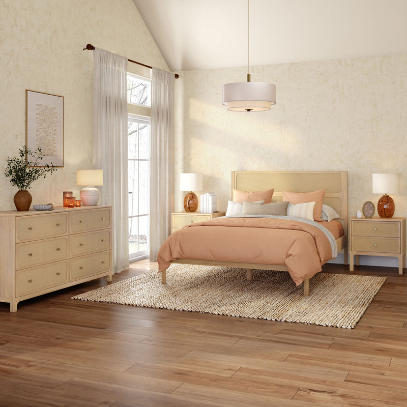 Warm minimalist boho bedroom with light wood bed frame and dresser, peach duvet and layered pillows, woven jute rug, rattan nightstands with lamps, sheer curtains and pendant light