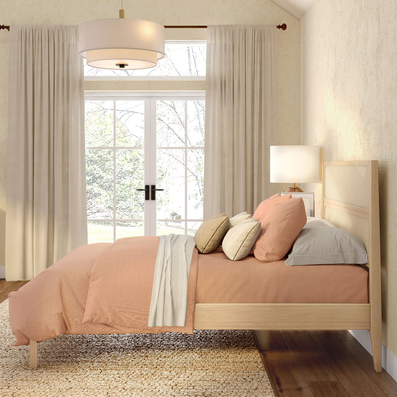 Cozy modern bedroom with peach duvet on light wood platform bed, neutral curtains, bedside lamp and large window letting in natural light, minimalist farmhouse decor