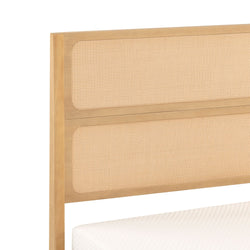Close-up of natural wood cane headboard with woven rattan panels and light wood frame, mattress edge visible, modern boho bedroom furniture