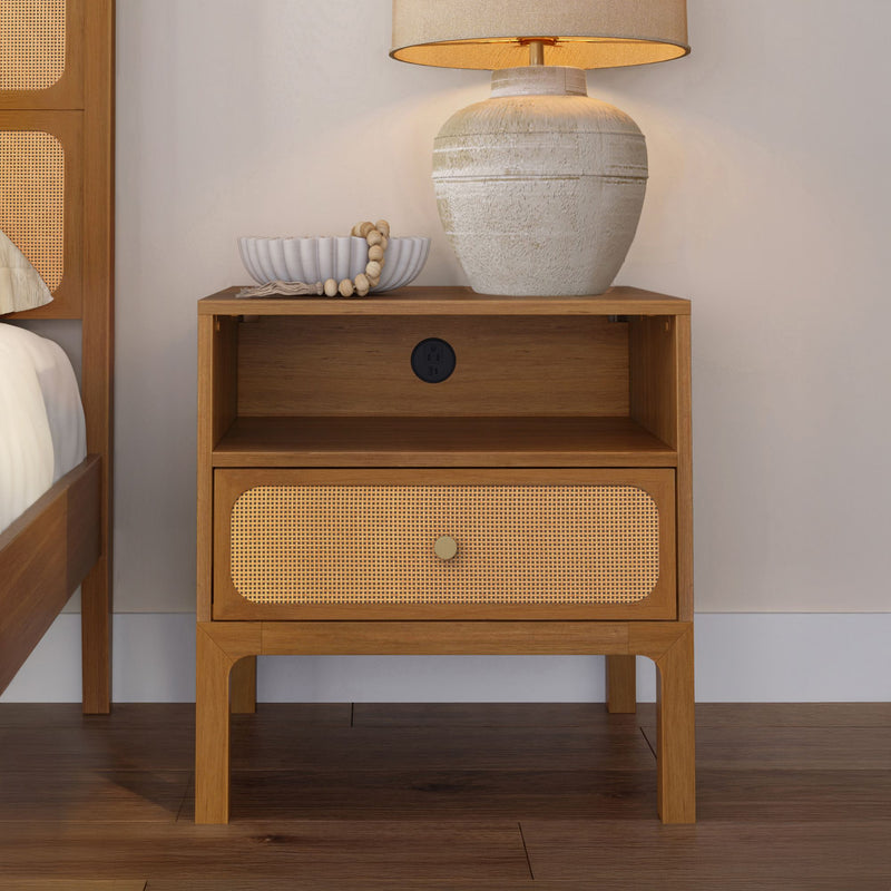 Mid-century modern wooden nightstand with woven rattan drawer, ceramic table lamp and decorative bowl in a neutral bedroom