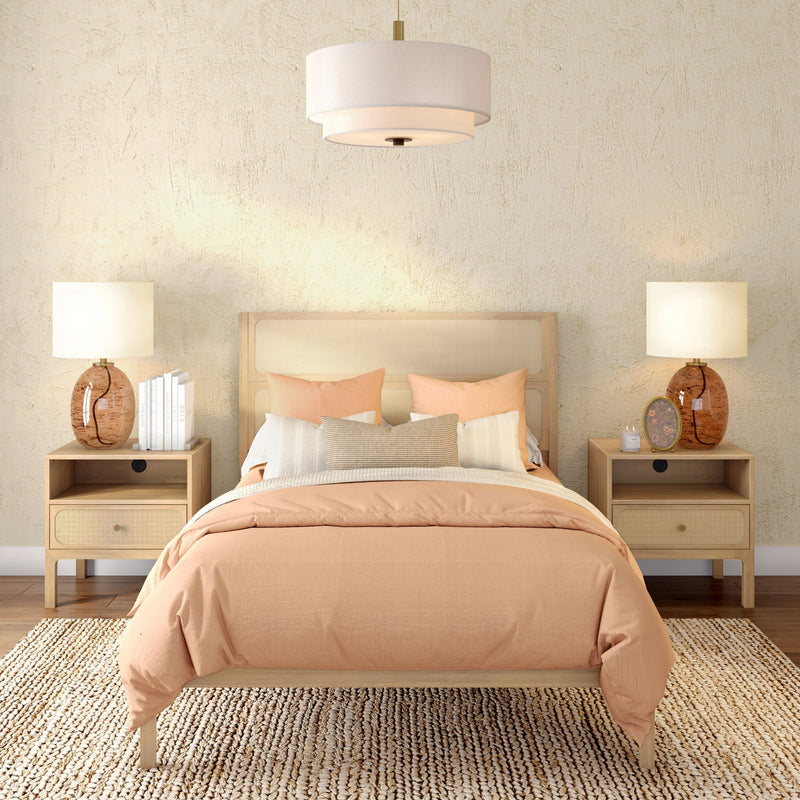 Modern boho bedroom with peach duvet and accent pillows, rattan headboard, wooden nightstands with amber glass lamps, pendant light, textured beige plaster wall and woven rug.