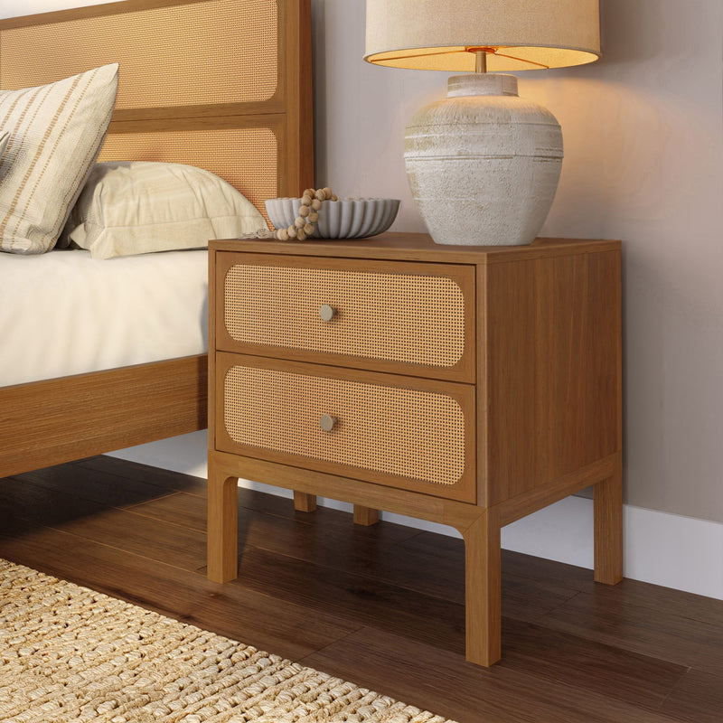 Mid-century modern wood two-drawer nightstand with rattan cane fronts and ceramic lamp beside bed in neutral bedroom