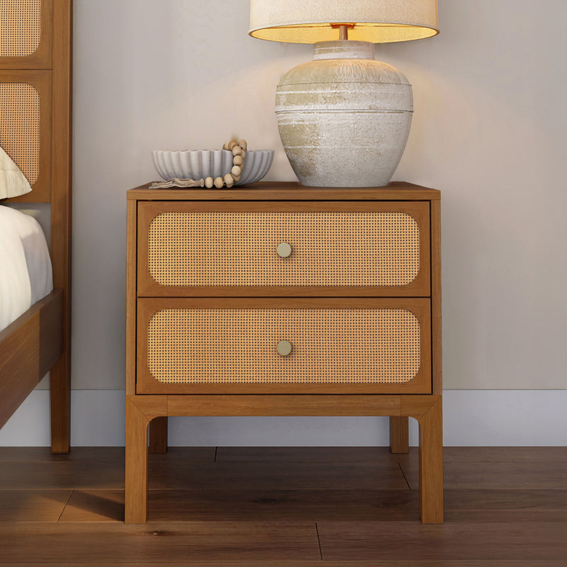 Mid-century modern rattan cane two-drawer wooden nightstand with ceramic bedside lamp and decorative bowl in styled bedroom decor