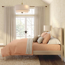 Cozy neutral master bedroom interior design with peach bedding, wooden platform bed, layered pillows, bedside lamp, textured rug, and large French doors with beige curtains and pendant light