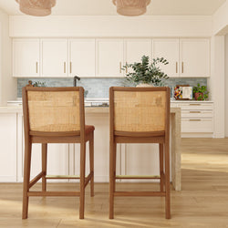 Bright modern kitchen island with two woven rattan bar stools, white shaker cabinets, blue subway tile backsplash, pendant lights and hardwood floors
