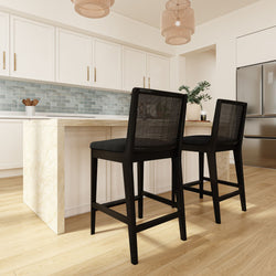 Modern kitchen interior with island, black bar stools, white cabinets, and stainless steel appliances.