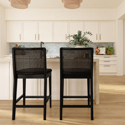 Modern kitchen island with two black bar stools, white cabinets, blue subway tile backsplash, woven pendants, potted plant.