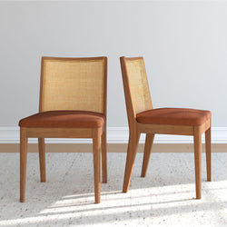 Pair of mid-century modern light oak dining chairs with rattan cane backs and brown upholstered seats in a neutral room