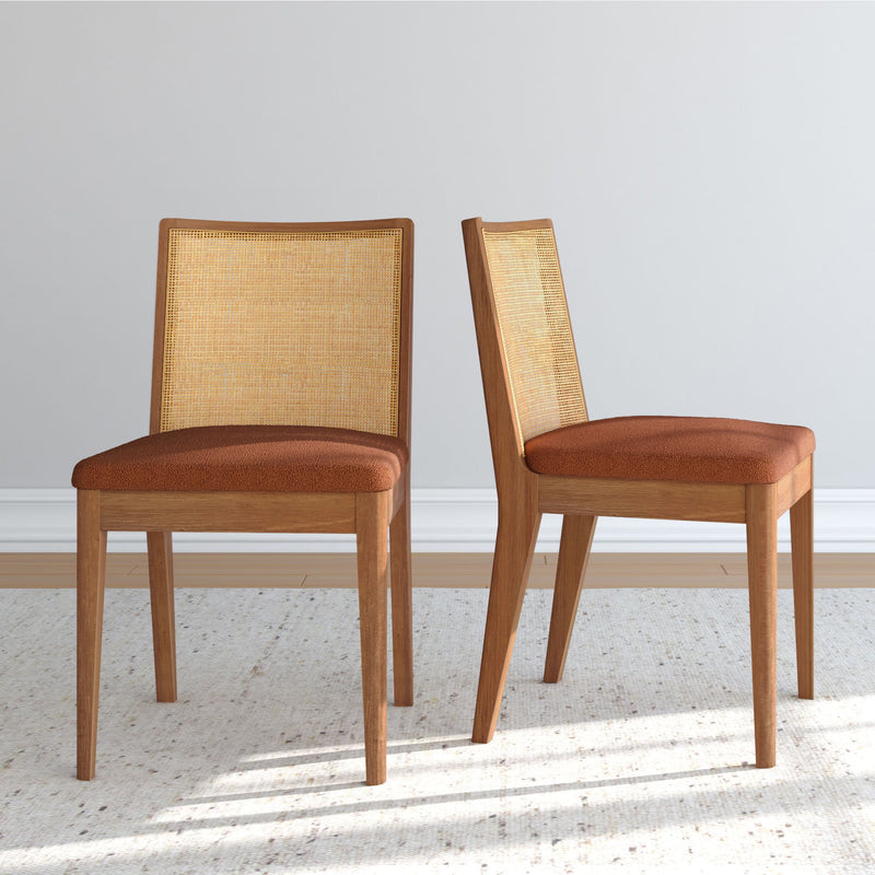 Pair of mid-century modern light oak dining chairs with rattan cane backs and brown upholstered seats in a neutral room