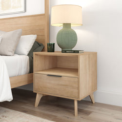 Mid-century modern wooden nightstand with lamp beside cozy bed in stylish bedroom.