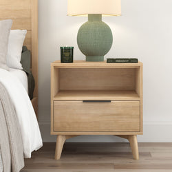 Wooden bedside table with a drawer, featuring a green lamp and candle, modern bedroom decor.