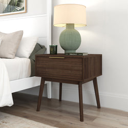 Mid-century modern wooden nightstand with lamp next to a cozy bed in a stylish bedroom.