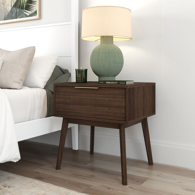 Mid-century modern wooden nightstand with lamp next to a cozy bed in a stylish bedroom.