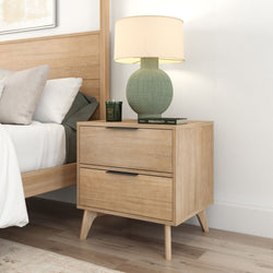 Modern wooden nightstand with drawers and lamp in a stylish bedroom setting.