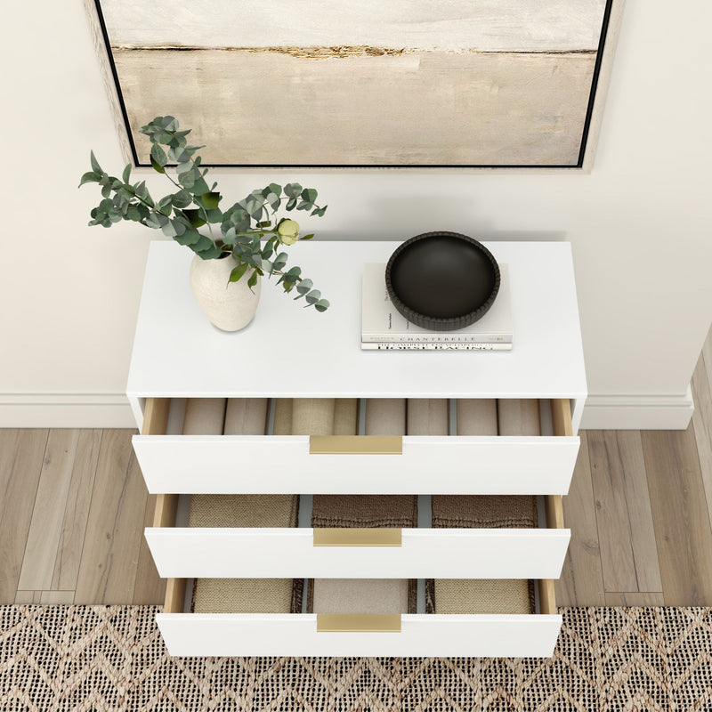 Modern white 3-drawer dresser with gold handles, folded beige linens, eucalyptus vase and black bowl, neutral entryway decor