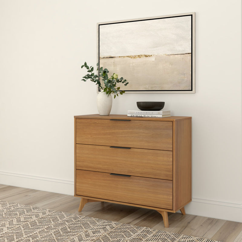 Mid-century modern wood dresser with three drawers, decorated with a vase and abstract art, enhancing living room decor.