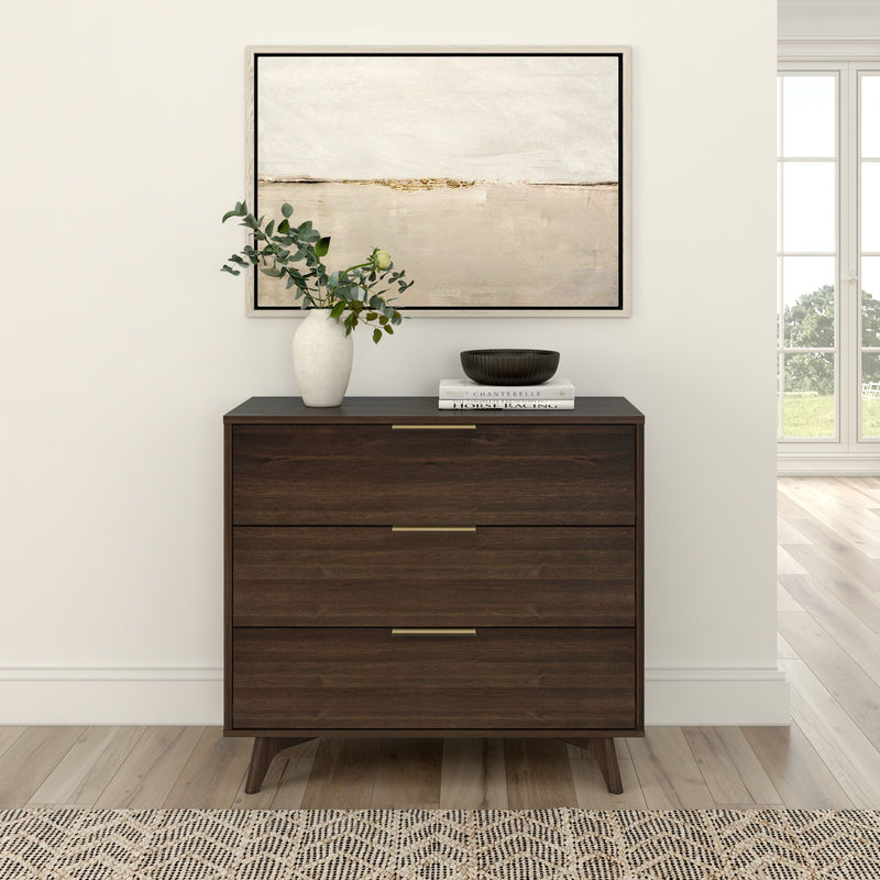 Wooden dresser with three drawers and decorative items, including a vase and books, in a modern living room setting with abstract wall art.