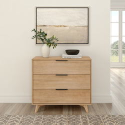 Modern minimalist wooden dresser with artwork, vase, and books in bright living room.