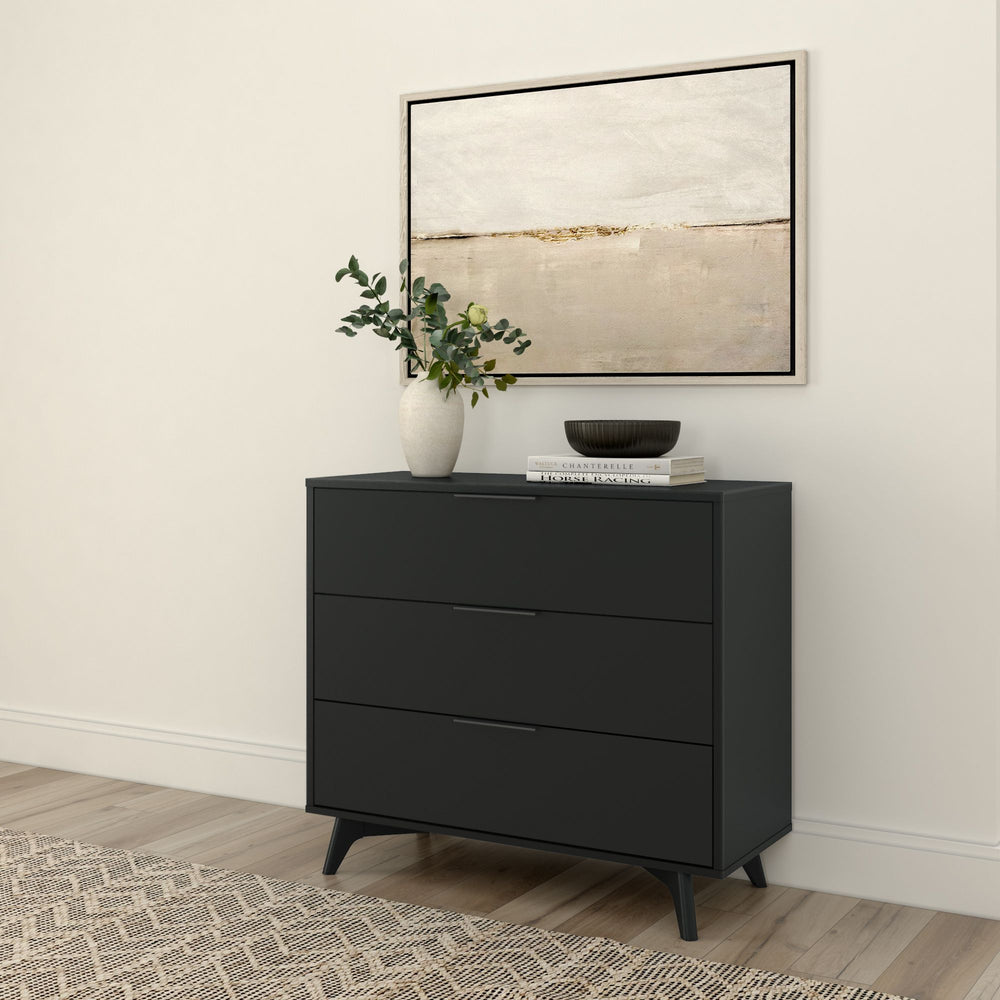 Modern black dresser with decorative vase and books against a minimalist wall with abstract art.