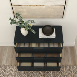 Modern black dresser with open drawers and a decorative vase with green foliage on top, placed on a wooden floor with a textured rug.
