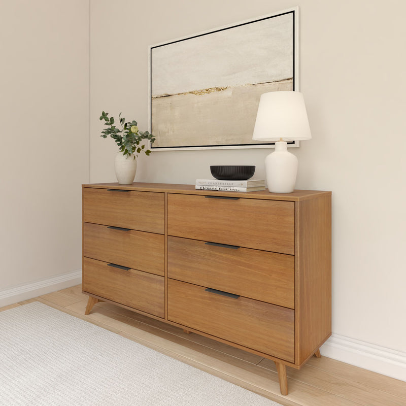 Mid-century modern six-drawer wooden dresser with warm wood finish in minimalist bedroom, styled with white table lamp, ceramic vase of eucalyptus, black decorative bowl, stacked books and abstract wall art