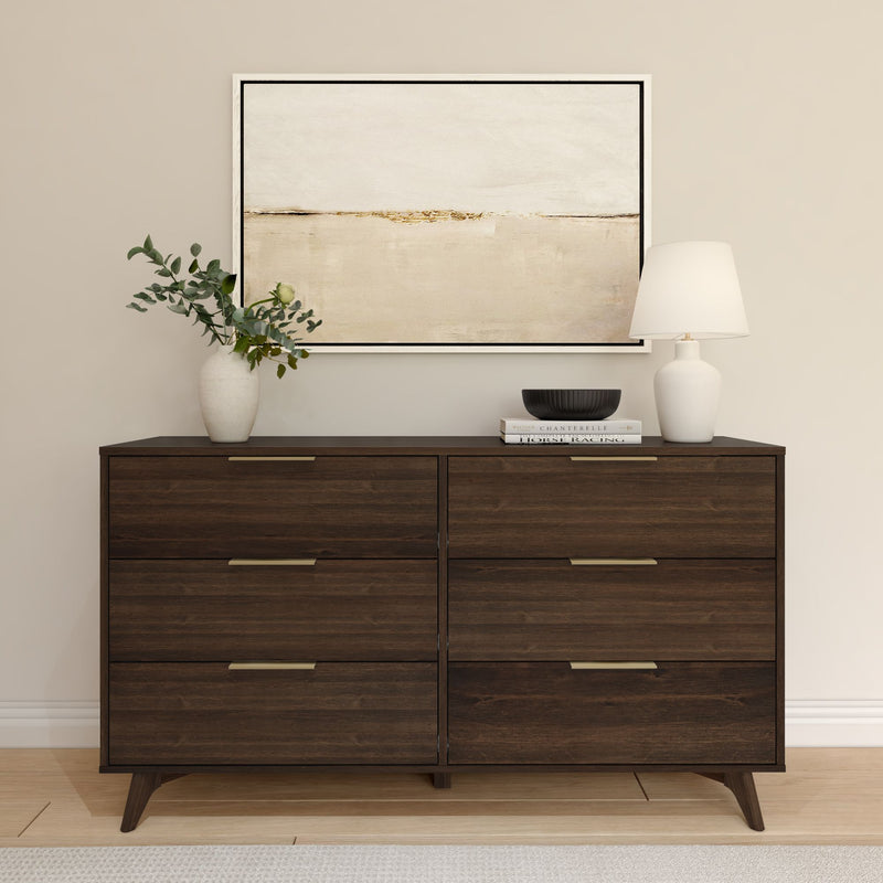Modern dark wood dresser with six drawers, featuring minimalist decor including a potted plant, books, and a table lamp, beneath an abstract wall art piece.