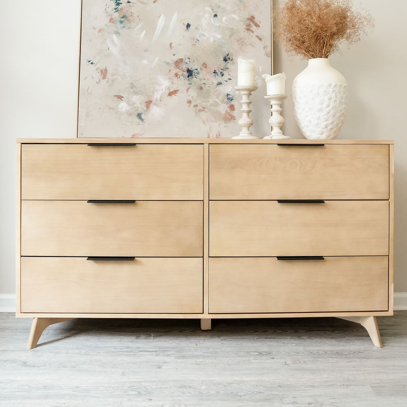 Modern wooden dresser with six drawers, decorative vase, and candles on top in a minimalist room setting.