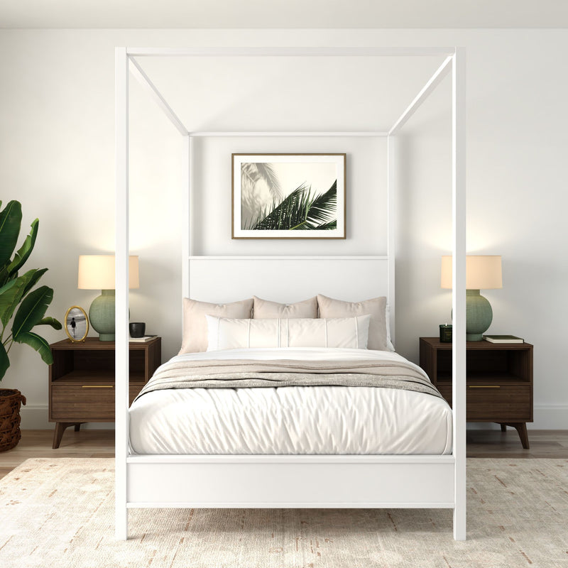 Modern minimalist bedroom with white four-poster canopy bed, neutral bedding, wooden nightstands, green table lamps, potted plant and framed palm leaf art