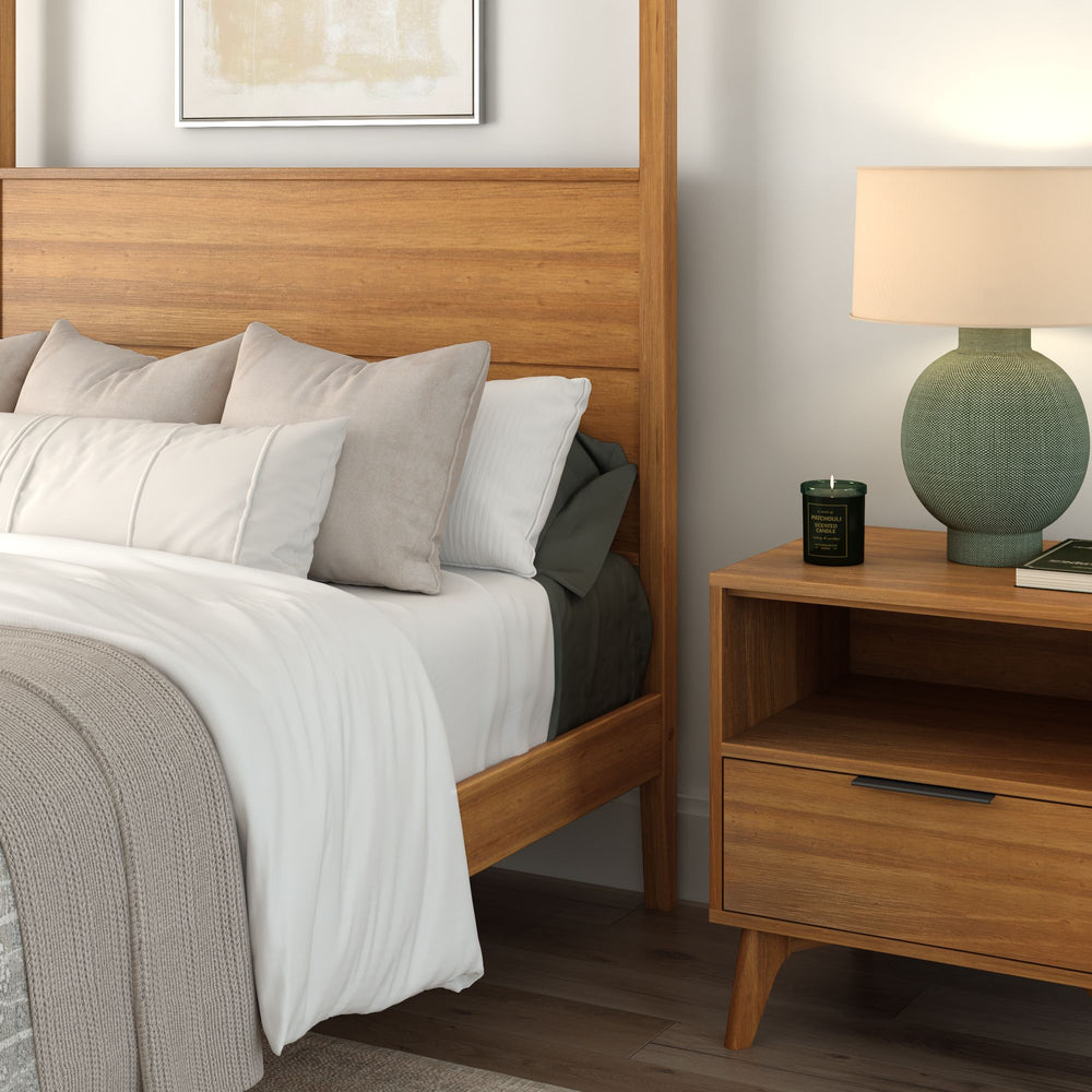 Mid-century modern bedroom with wooden bed frame, cozy pillows, and a stylish nightstand with a lamp and candle.