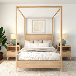 Minimalist Scandinavian master bedroom with light-wood four-poster bed, neutral bedding, matching nightstands, green table lamps and potted plant.